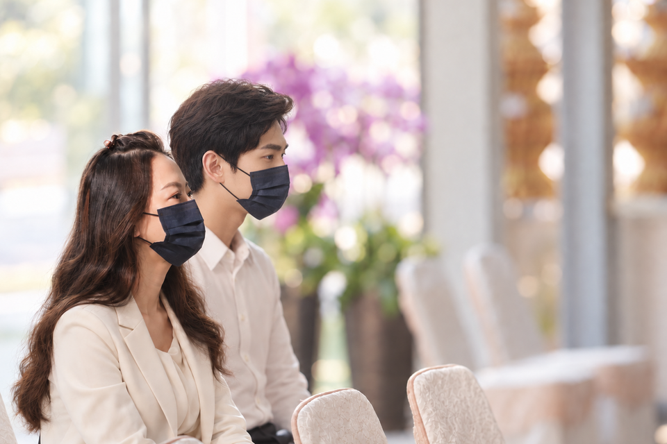 穿著素色服裝的男女於告別式場內參與追思